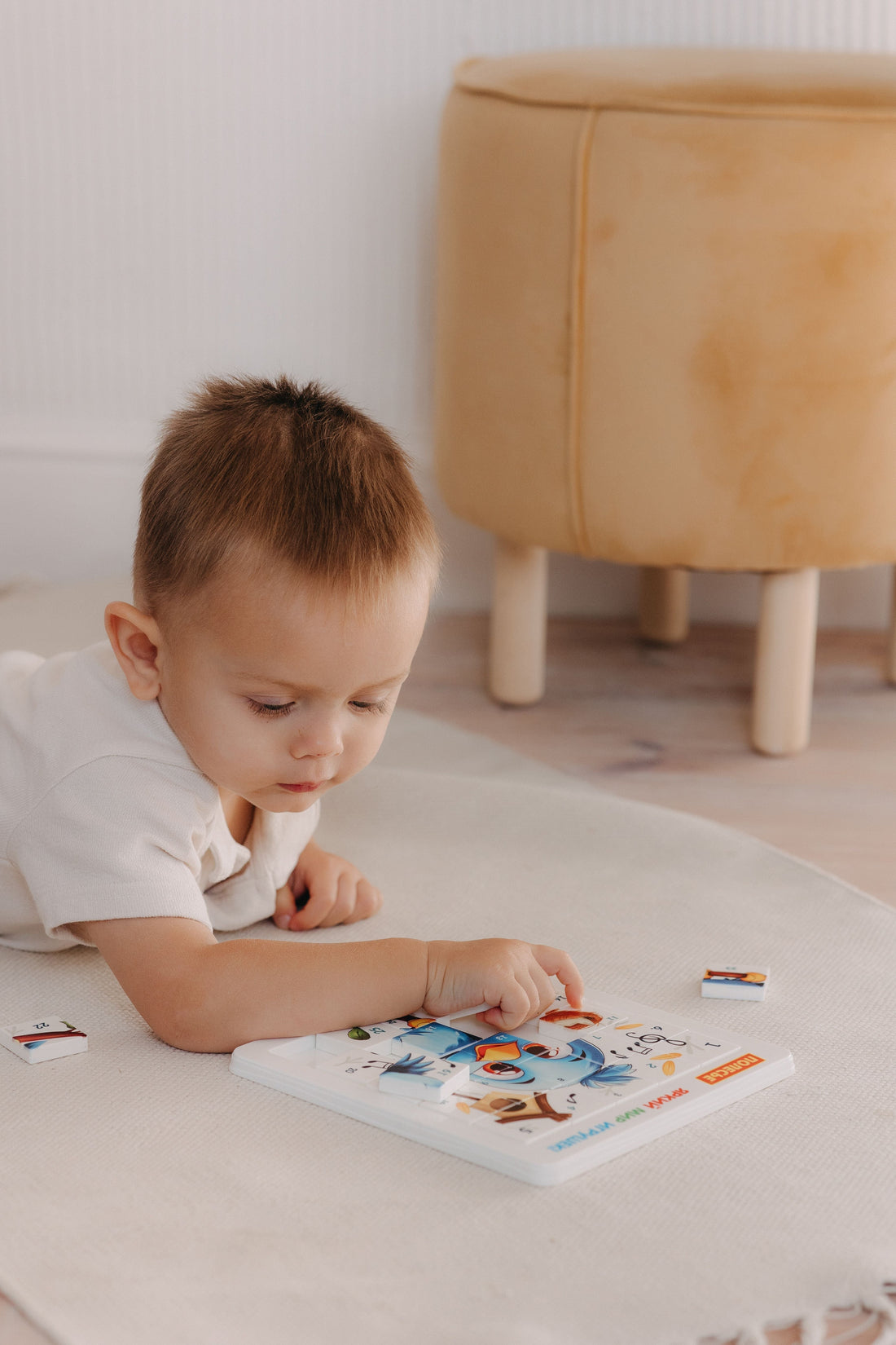 Chłopiec układający puzzle na dywanie